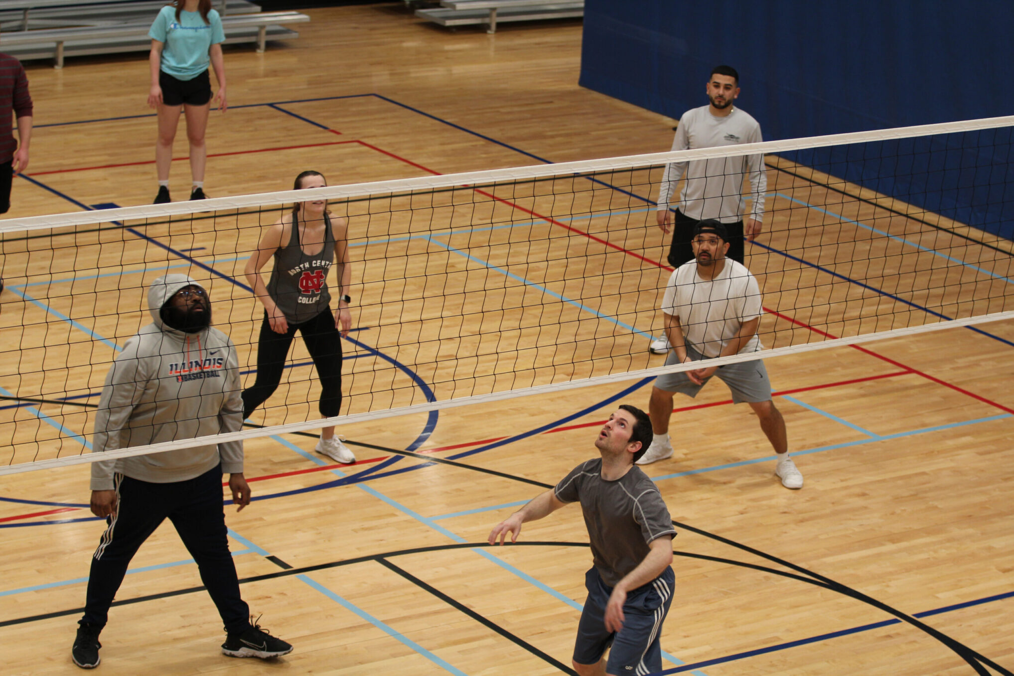 Adults playing volleyball in a gym volleyball court